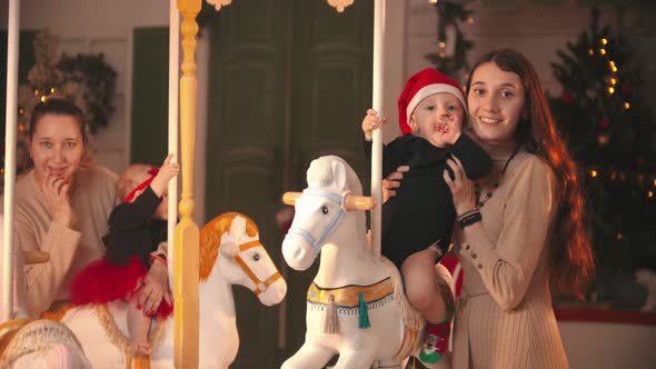 Two Babies Sitting on the Carousel Horses