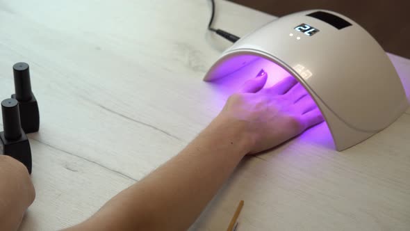 Girl Placed Hand Under an Nail Polish Curing Lamp and Waits for the Nail Polish to Harden