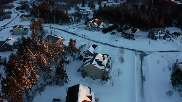 Winter aerial view looking down on snow covered homes in a suburban subdivision.