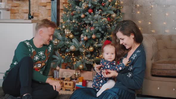 Young Family Playing with Their Little Daughter Near Christmas Tree at Home