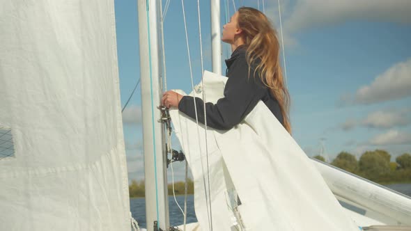 A Beautiful Young Sportswoman Studies the Rigging and Rigging of a Sports Yacht. Learning To Raise a