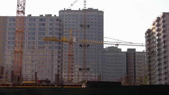 Yellow Cranes and Highrise Buildings Over Ray Sky Background