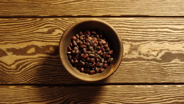 Unpeeled pine nuts appear in wooden cup and full this cup