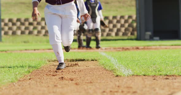 Low section of female baseball players playing on the field, hitter running for base