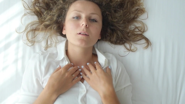 Top View Of Young Woman Sending Air Kiss Lying On Bed
