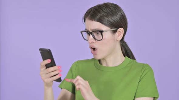 Shocked Young Woman Using Cellphone on Pink Background