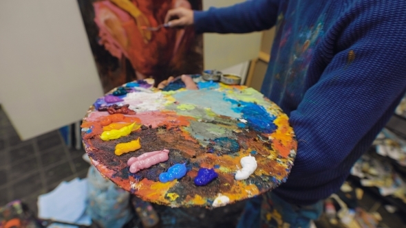 Artist Paints a Picture Of Oil Paint Brush In Hand With Palette 