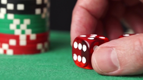 Red Dice And Casino Chips In Hand On Green Table