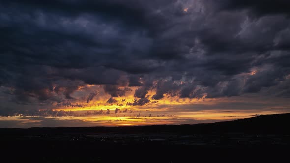 Panning drone shot of a golden but mysterious sunset, storm rolling in.