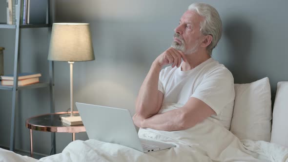 Old Man with Laptop Thinking in Bed 