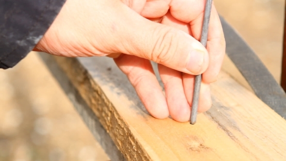 Man Hammers a Nail Into a Plank
