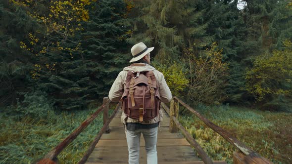 Adventurous Man in Hat with Backpack Hiking on Trail Up Peaceful Lush High Elevation Green Autumn