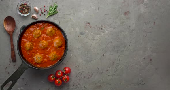 Cooking meatballs with tomato sauce in black pan