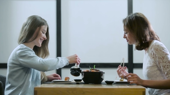 Two Girls Gossiping In a Japanese Restaurant