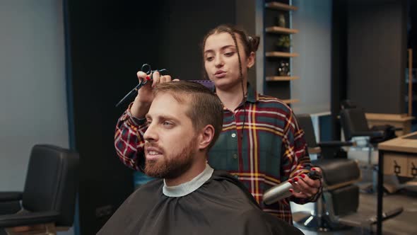 Barbershop: a woman barber cuts a client's man's hair