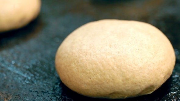 A Baker Is Greasing a Bun With Oil.