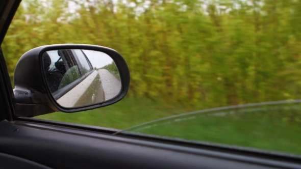Reflected In The Side Mirror Of a Car Traveling