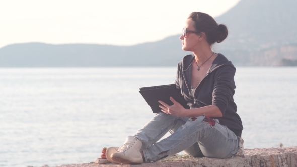 Woman Using a Tablet On The Beach During Sunset