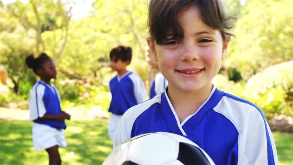 Smiling girl holding a football in park