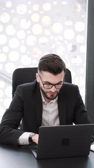 Handsome Young Man Working at Office Desk with Laptop
