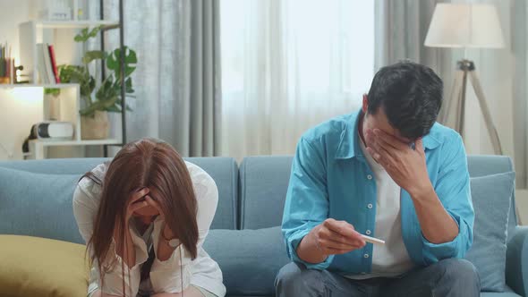 Frustrated Asian Couple After Checking A Pregnancy Test In Living Room At Home