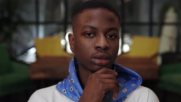 Close Up View of Young Serious Afro American Guy Propping and Turning Head While Looking to Camera