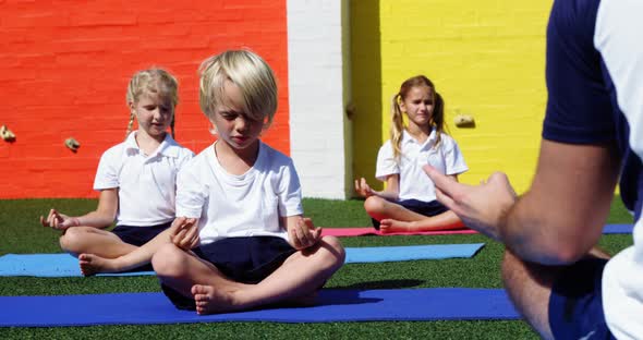 Yoga instructor instructing children in performing yoga