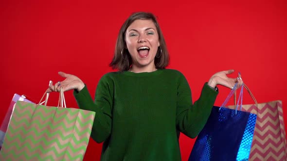 Happy Young Woman with Colorful Paper Bags After Shopping Isolated on Red 