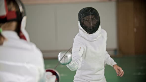 Two Young Women at Fencing Training in the School Gym - One Woman Attacks and Another Defends