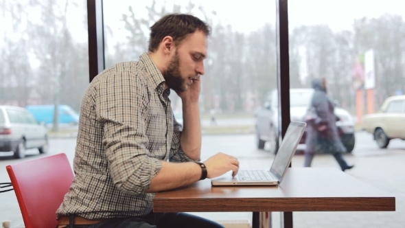 Man Working On Laptop In Cafe