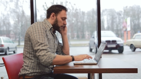 Man Working On Laptop In Cafe