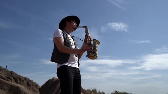 Saxophonist Is Playing Melody on Nature, Man Is Standing on Rock Against Picturesque Sky