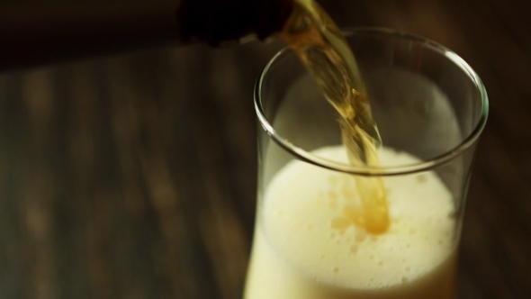 Pour The Flavored Beer Into a Glass On Dark Wooden Table With Copy Space