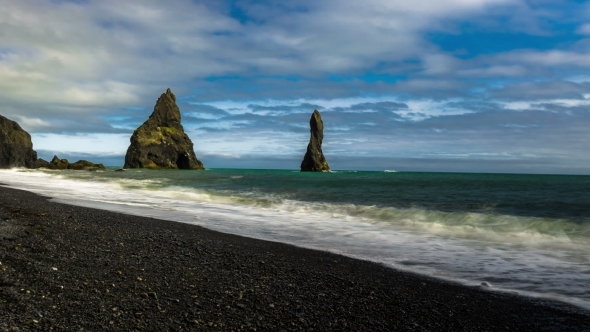 Waves Breaking On The Black Sand Beach. Basalt Columns