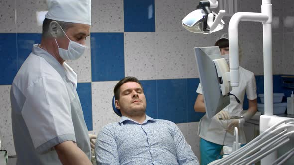 Male Client Having Her Teeth Examined By Dentist