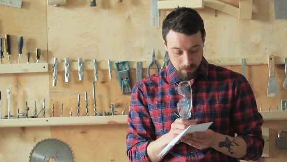 Man In The Carpenter's Workshop Writing a Draft On Paper