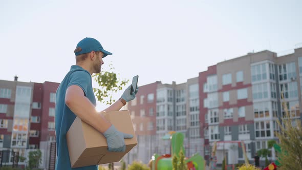 Male Courier Man is Looking for Mobile Phone to Deliver Address of Food From a Shop