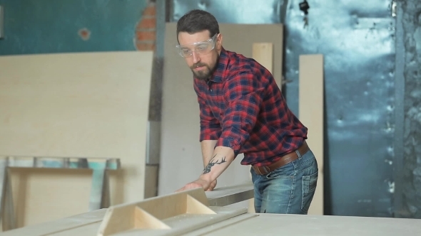 Man Sawing a Board In a Carpentry Workshop Using a Circular Saw