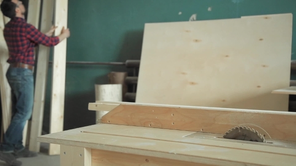 Carpenter Works With Wood And a Saw In Workshop