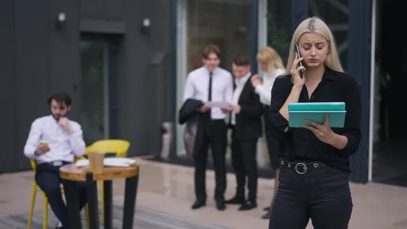 Stressed Worried Young Woman Standing with Tablet Talking on Phone in Slow Motion As Blurred