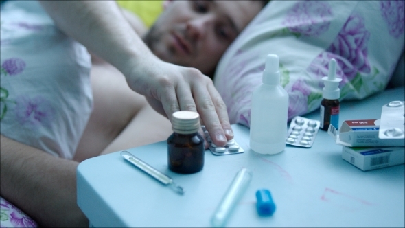 Sick Man In Bed Taking Pills