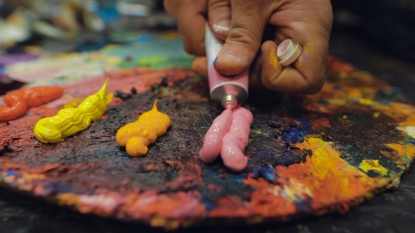 An Artist Squeezes Out Some Pink Paint From a Tube Of Oil Paint. alt