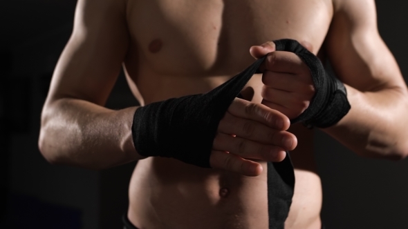  Mid Section Of a Shirtless Muscular Man Binds Bandage On His Hand