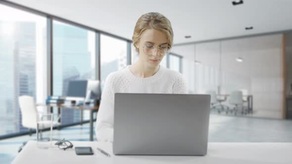 Woman Is Using Laptop While Sitting at Her Desk. Young European Businesswoman Is Sitting in the