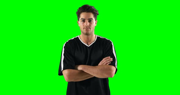 Confident football player standing against green screen