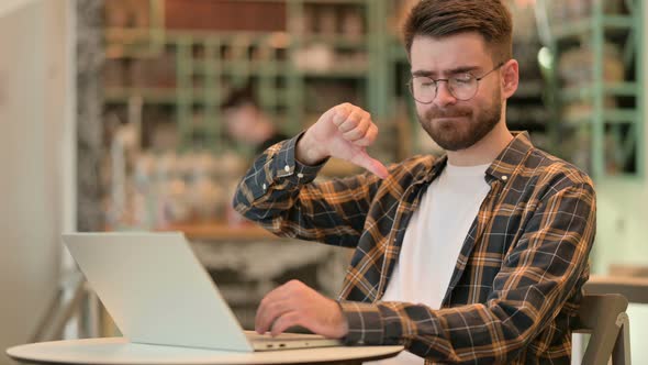 Thumbs Down By Young Man Working in Cafe 