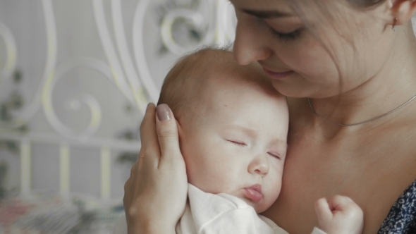 Young Mother Holding Her Newborn Sleeping Child