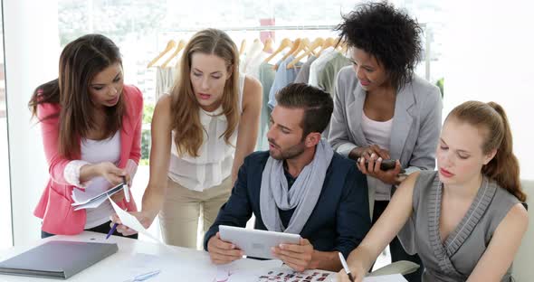 Busy fashion design team working together at table