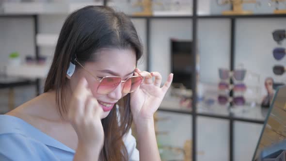 Optical shop concept. Young Asian women are happily choosing sunglasses