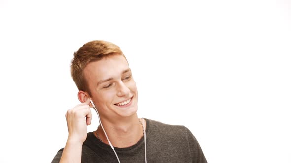Young Handsome Man Singing Dancing Listening Music in Headphones Over White Background